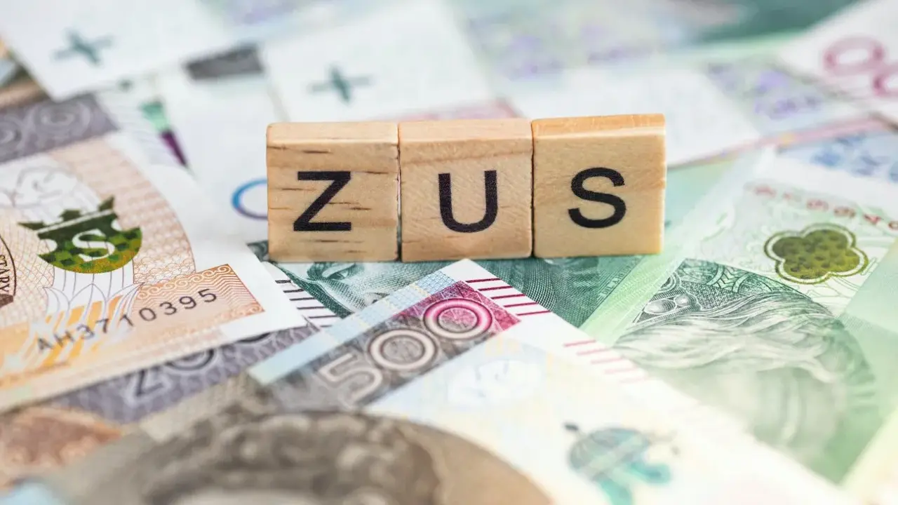 Drewniane klocki z napisem ZUS na tle polskich banknotów. Dowiedz się, ile można dorobić do renty rodzinnej, nie przekraczając limitów ZUS.