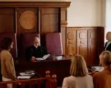 Sąd rozpatruje sprawę z art. 233 kk. Sędzia w todze, oskarżeni i świadkowie czekają na werdykt.