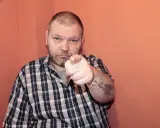 Mężczyzna w kratę wskazuje palcem, na ramieniu ma tatuaż Indianina. To jest 234 kk.