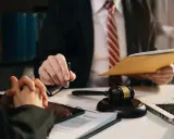 Prawnik omawia służebność osobistą, trzymając dokumenty i długopis. Obok leży młotek sędziowski.