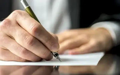 Dłoń pisze piórem na papierze, być może dokumentując służebność mieszkania.