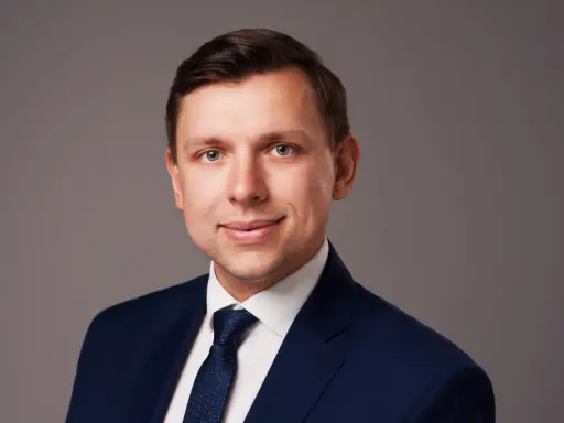 Portret mężczyzny w granatowym garniturze i białej koszuli z krawatem.
