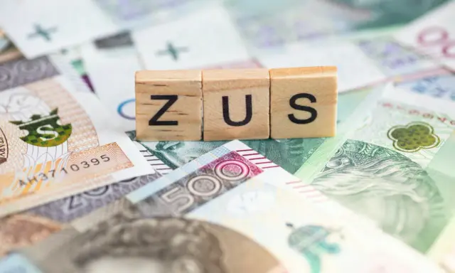 Drewniane klocki z napisem ZUS na tle polskich banknotów. Dowiedz się, ile można dorobić do renty rodzinnej, nie przekraczając limitów ZUS.