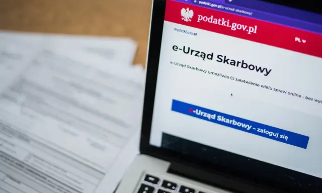 Na ekranie laptopa widoczny jest portal e-Urząd Skarbowy. Obok leżą dokumenty, które mogą zawierać identyfikator zobowiązania.