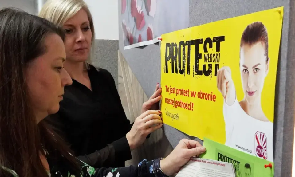 Dwie kobiety wieszają plakat "PROTEST WŁOSKI" na tablicy. Hasło głosi: "To jest protest w obronie naszej godności!".