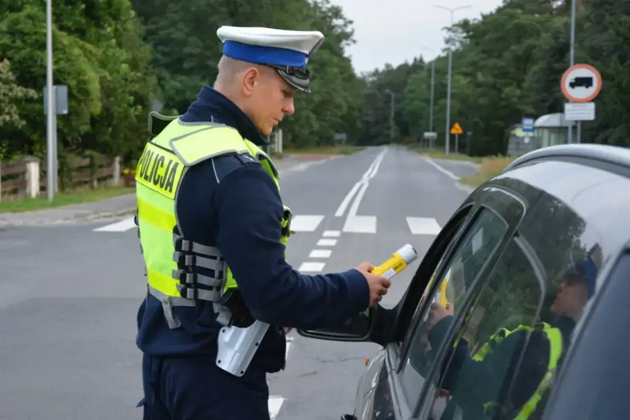 Policjant z alkomatem przy samochodzie. Kierowca może spodziewać się konfiskaty samochodu, jeśli wynik będzie pozytywny.