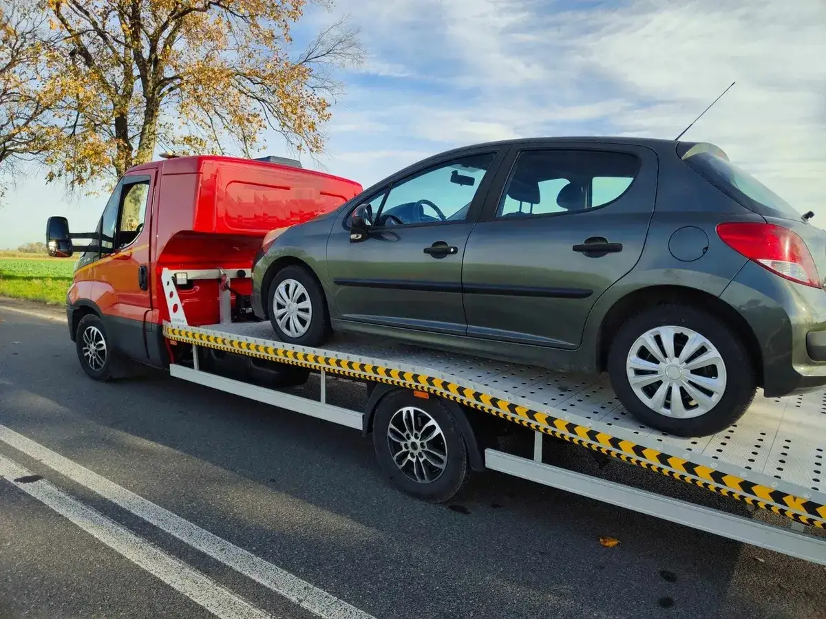 Ciemnoszary samochód na lawecie. Wygląda na to, że czeka go konfiskata samochodu.