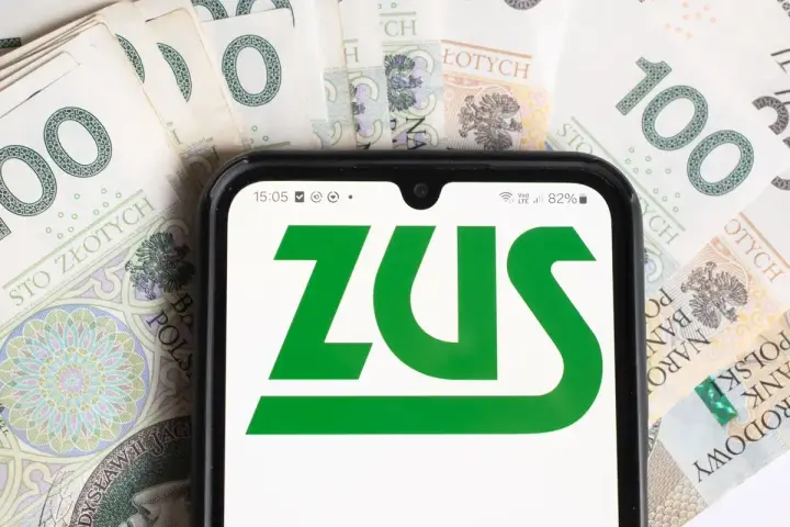 Telefon z logo ZUS na tle banknotów 100 zł. Symbolizuje to przyszłość i emeryturę socjalną.